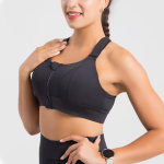Femme portant une brassière de sport noire avec fermeture éclair, posant de profil. Accessoire montre au poignet. Mode fitness, tenue sportive.